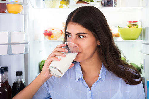 Portrait Of A Smiling Young Woman Holding Glass Of Milk
