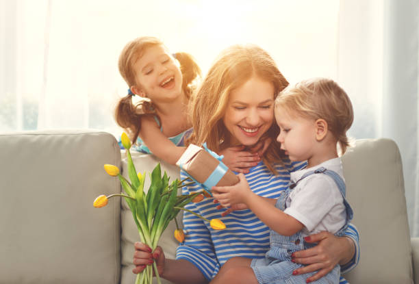 szczęśliwy dzień matki! dzieci gratulują mamom i dają jej prezent i kwiaty - child spring family little girls zdjęcia i obrazy z banku zdjęć
