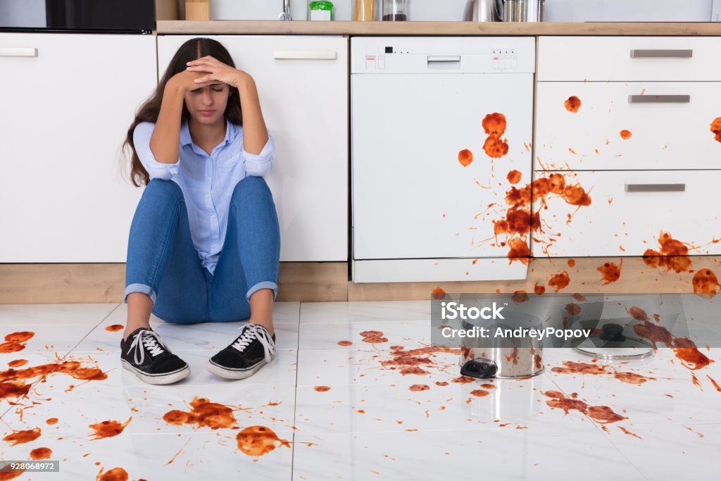 Woman Sitting On Kitchen Floor With Spilled Food Unhappy Woman Sitting On Kitchen Floor With Spilled Food In Kitchen Kitchen Stock Photo