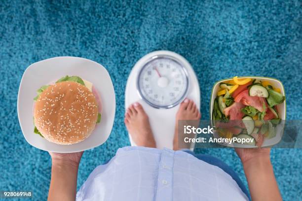 Person Holding Plates Of Burger And Salad Stock Photo - Download Image Now - Dieting, Weight Scale, Healthy Eating
