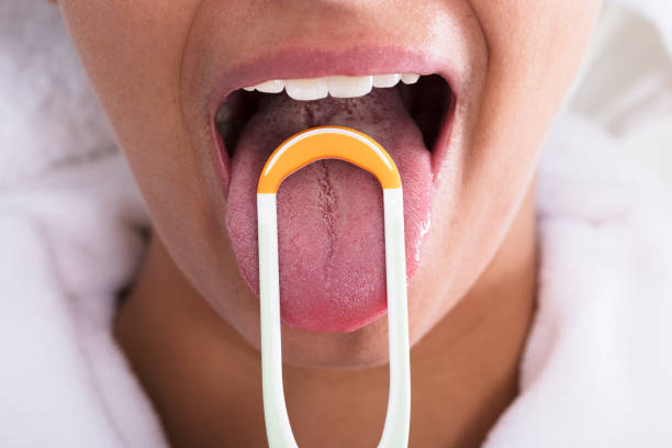 Woman Cleaning Tongue Photo Of Young Woman Cleaning Tongue With Cleaner tongue stock pictures, royalty-free photos & images