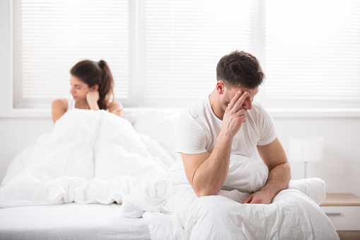 Worried Young Couple Sitting On Bed At Home