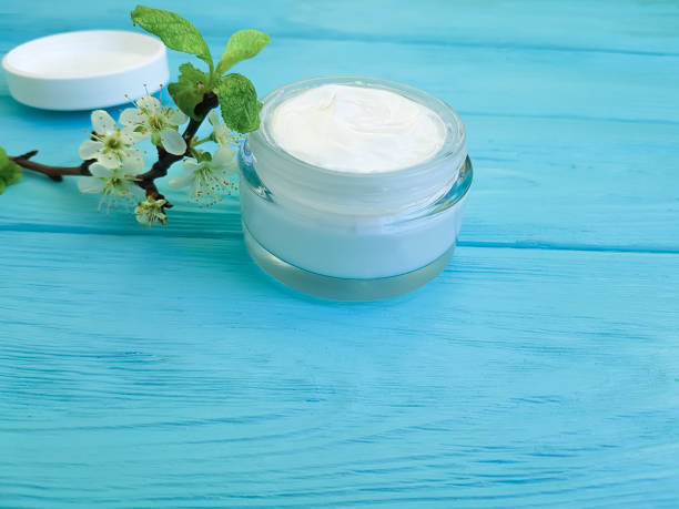 istock cream cosmetic, cherry branch blossoming blue wood background 928073926