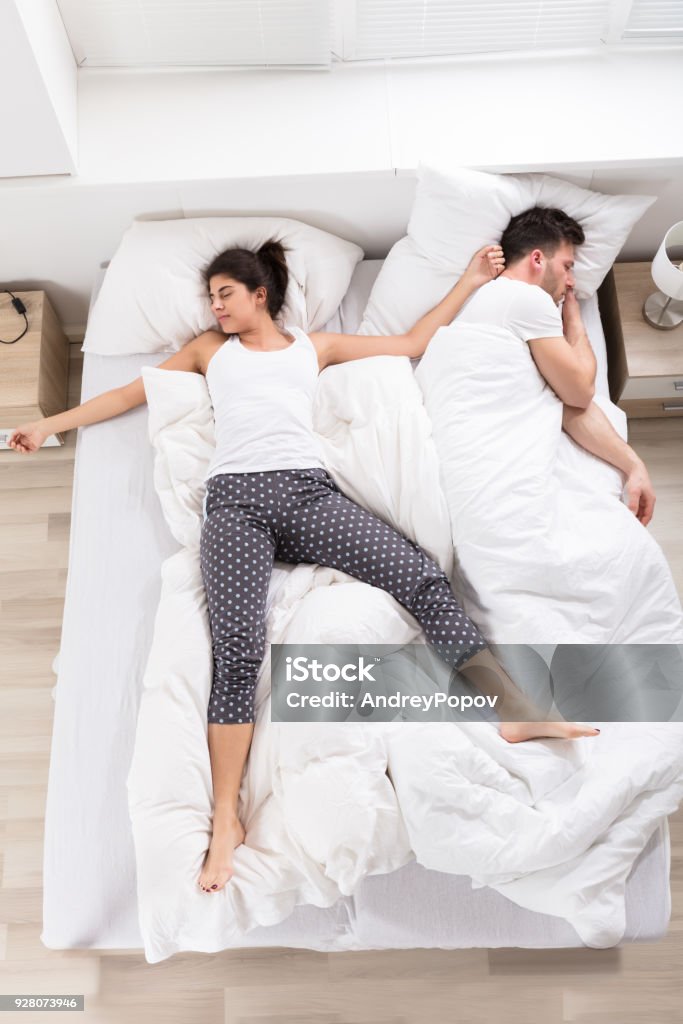 Young Woman Sleeping Beside Her Husband Overhead View Of Young Woman Sleeping Beside Her Husband On Bed Adult Stock Photo
