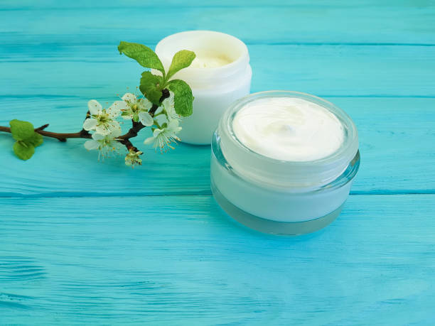 istock cream cosmetic, cherry branch blossoming blue wood background 928076714