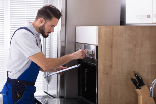 istock Electrician Writing On Clipboard In Front Of Oven 928076854