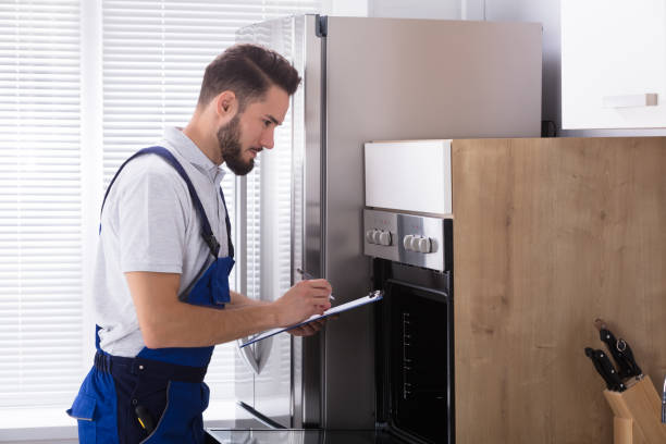 istock Electrician Writing On Clipboard In Front Of Oven 928076856