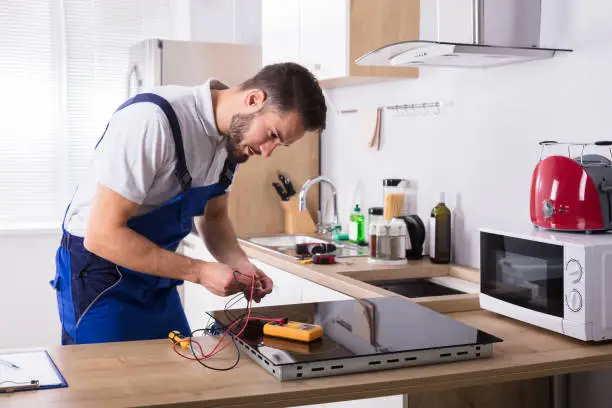 Photo of Technician Repairing Induction Stove In Kitchen