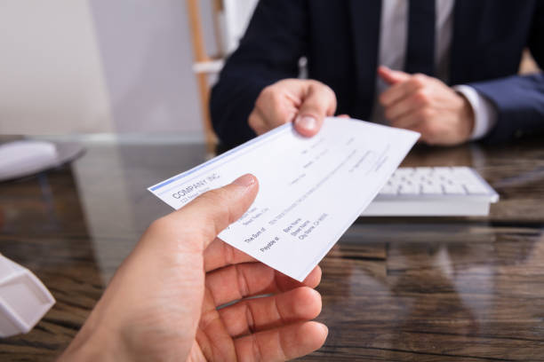 Businessperson Giving Cheque To Colleague Close-up Of A Businessperson's Hand Giving Cheque To Colleague At Workplace wages stock pictures, royalty-free photos & images