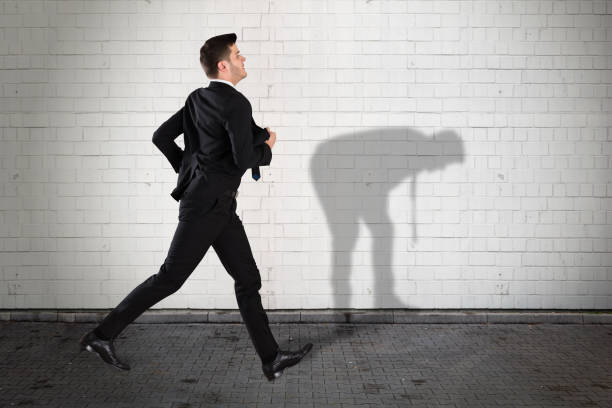 istock Businessman Running On Sidewalk With His Shadow On Wall 928081624