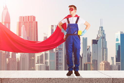 Young Male Janitor In Superhero Costume With Cleaning Equipments Standing On Top Of Building