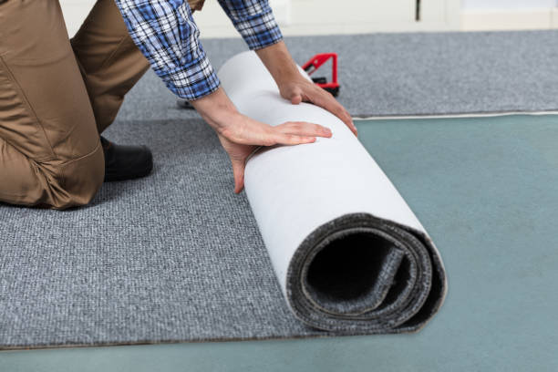 istock Male Handyman Rolling Carpet On Floor 928084102