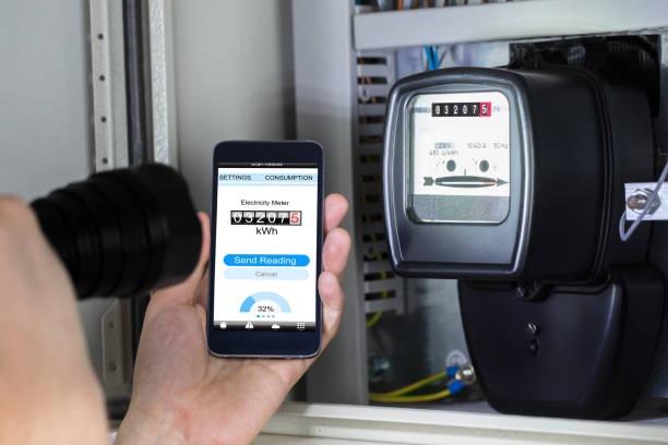 istock Man's Hand Holding Mobile Phone Showing Electric Meter Reading 928084152