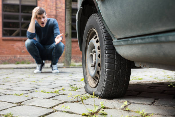 istock Crouched Man Pointing At Punctured Car Tire 928084262
