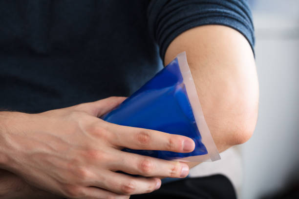 Person Applying Ice Gel Pack On An Injured Elbow Close-up Of A Person Applying Ice Gel Pack On An Injured Elbow At Home physical injury sport ice pain stock pictures, royalty-free photos & images