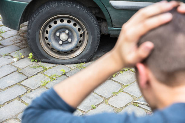 istock Worried Man Looking At Punctured Car Tire 928084294