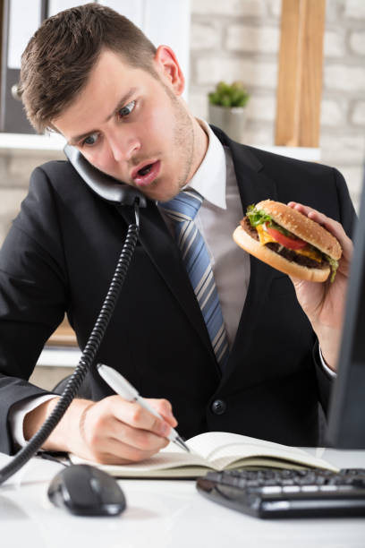 istock Business Man At Desk Eating Burger And Working 928084314