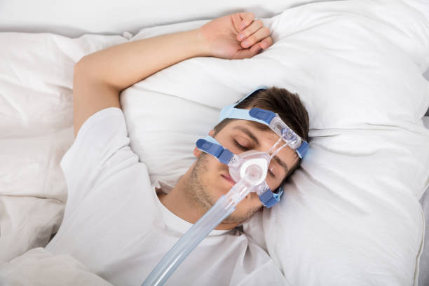 istock Man Lying On Bed With Sleeping Apnea And CPAP Machine 928084324