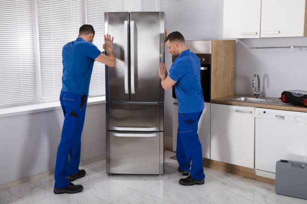 deux déménageurs placer le réfrigérateur dans la cuisine - déménageur photos et images de collection