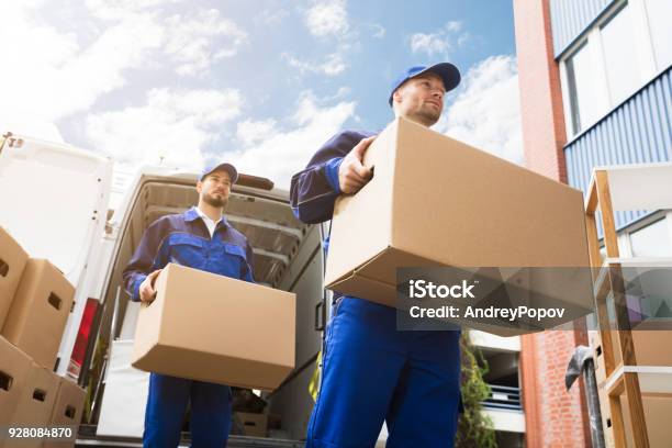 Closeup Of Two Delivery Men Carrying Cardboard Box Stock Photo - Download Image Now