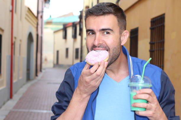 istock Man eating Donuts and drinking shake outdoors 928084936