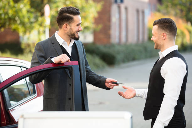 young businessman giving car key to valet - valet parking imagens e fotografias de stock