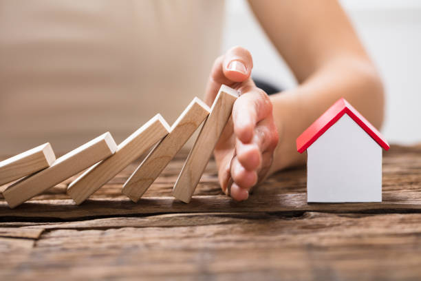 Human Hand Stopping The Wooden Blocks From Falling Close-up Of A Human Hand Stopping The Wooden Blocks From Falling On House Model hand stopping dominos stock pictures, royalty-free photos & images