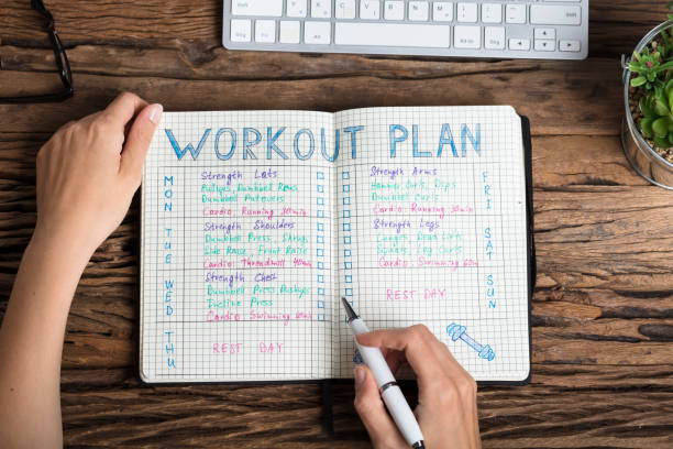 Human Hand Preparing Workout Plan Close-up Of A Human Hand Preparing Workout Plan On Grid Notebook routine stock pictures, royalty-free photos & images