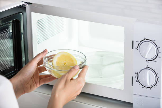 Woman Putting Bowl Of Slice Lemon In Microwave Oven Close-up Of Woman Putting Bowl Of Slice Lemon In Microwave Oven inside microwave stock pictures, royalty-free photos & images