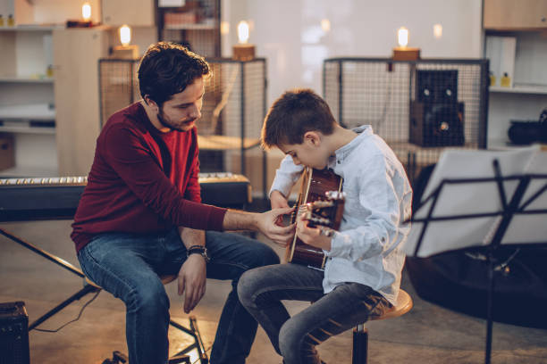 unterricht für gitarre in der musikschule spielen junge - music lessons stock-fotos und bilder