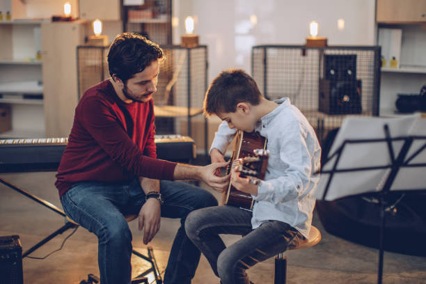 Boy teaching to play guitar in music school Boy teaching to play guitar in music school conservatory education building stock pictures, royalty-free photos & images