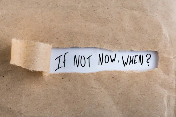 If Not Now When, appearing behind torn brown paper.