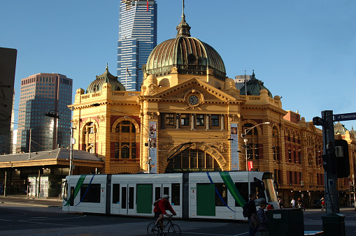 Pedestrians walk in front of Flinders Street Railway Station in Melbourne, Victoria, Australia on an overcast day.