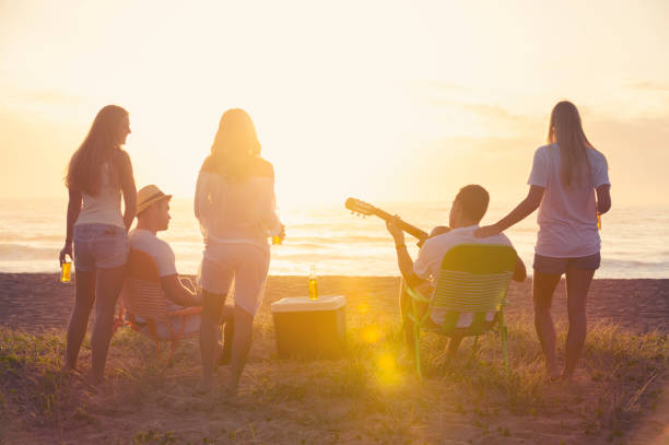 entspannte freunde-beach-party bei sonnenuntergang mit 5 personen. - spring break stock-fotos und bilder