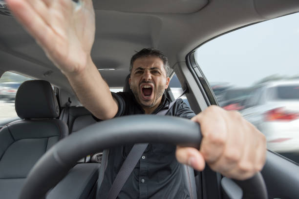 Young angry man driving his vehicle Wide angle look inside in the car of actually driving young male with hands in foreground. furious stock pictures, royalty-free photos & images