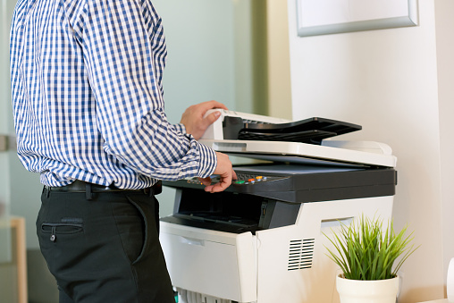 Close-up of office employee making copies of files with copy machine