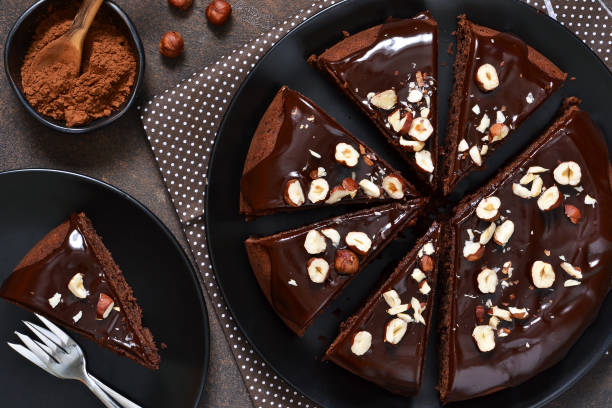 istock Chocolate cake with hot chocolate sauce and fried hazelnuts on a dark, concrete background. 928103716