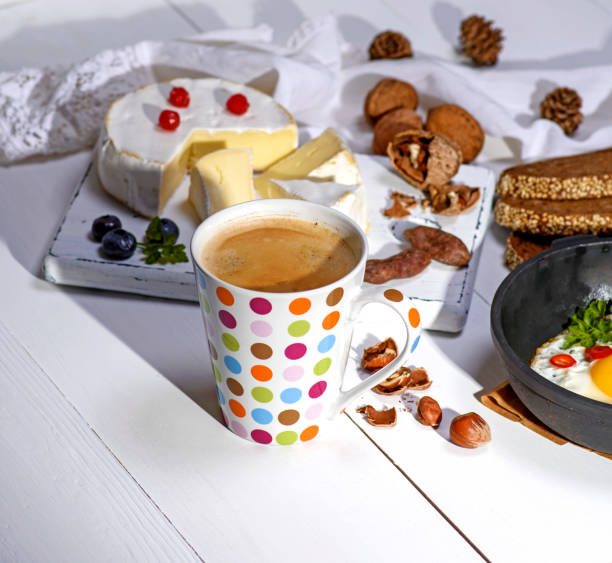 istock coffee with brown foam in a white ceramic mug, behind a round camembert cheese 928103812