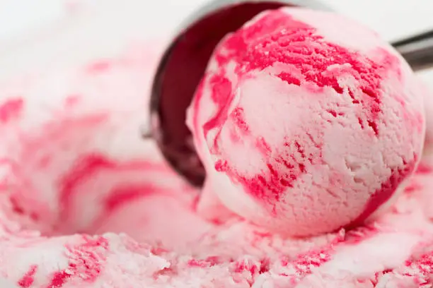 Ripple (vanilla raspberry or strawberry) ice cream  scooped out of a container with a utensil.