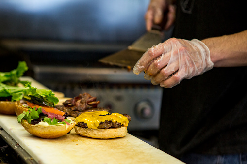 On a restaurant kitchen counter a chef prepares multiple hamburgers