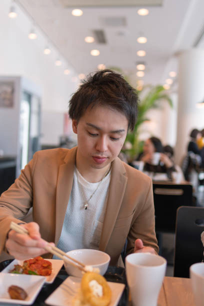 istock Young man in jacket eating lunch in cafe 928143388