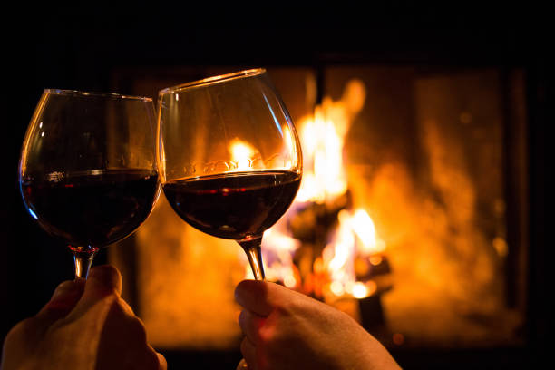 istock Couple holding pair of glasses with wine at fire pit 928146208