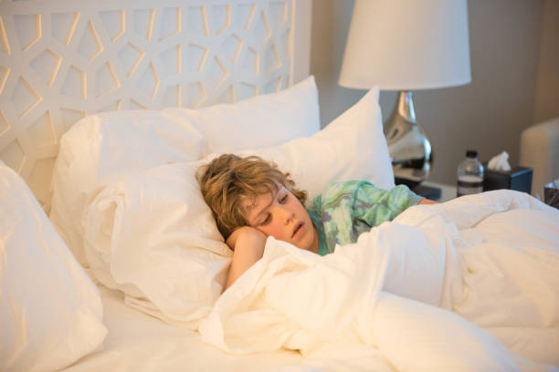 istock Young child sits in bed sick while trying to rest 928153526