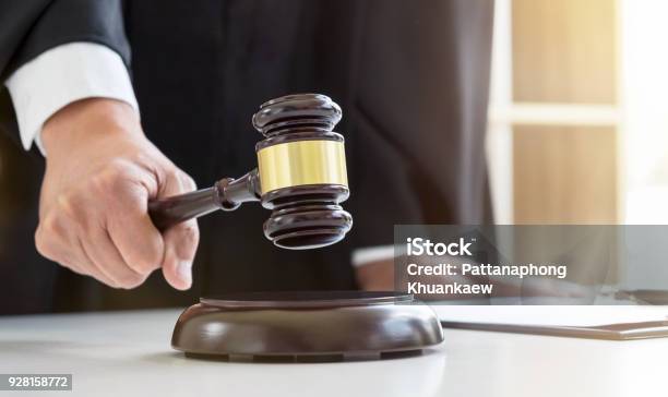 Close Up Of Male Lawyer Or Judge Hands Striking The Gavel On Sounding Block Working With Law Books Report The Case On Table In Modern Office Law And Justice Concept Stock Photo - Download Image Now