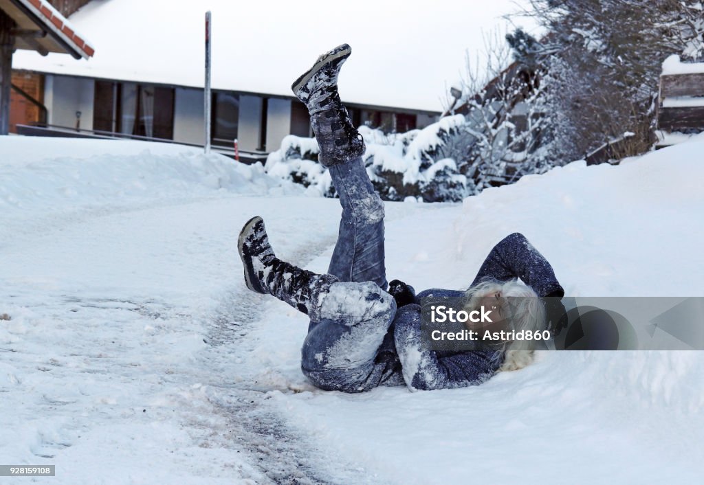 Une femme a glissé sur la route d’hiver, est tombé vers le bas et se blesse - Photo de Tomber libre de droits