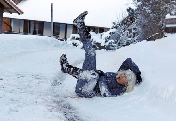 une femme a glissé sur la route d’hiver, est tombé vers le bas et se blesse - falling senior adult people one person photos et images de collection