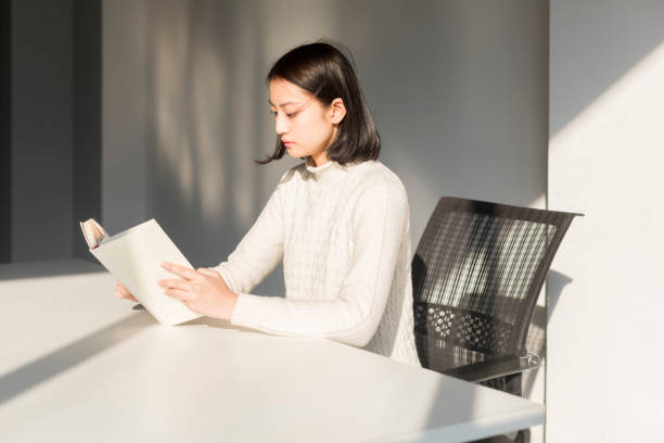 istock young woman reading a book at desk 928161956