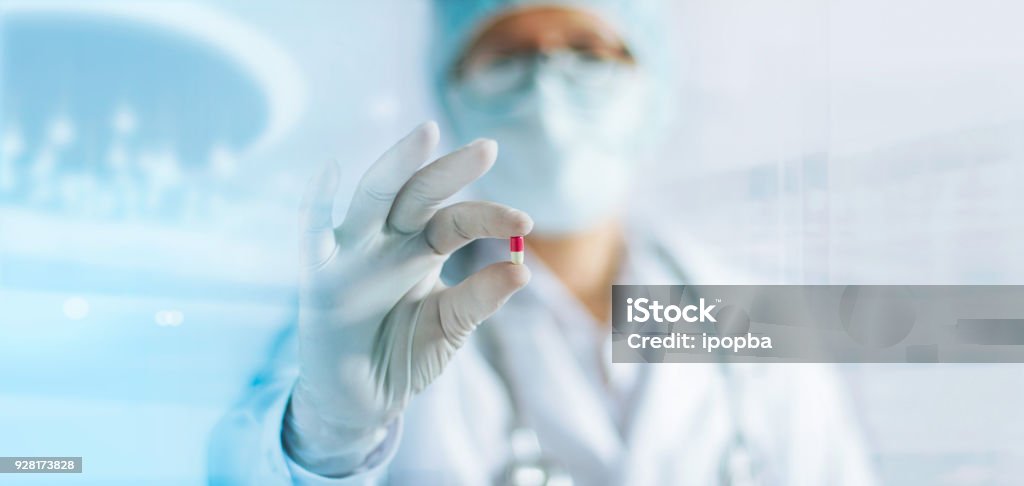 Medicine doctor holding a color capsule pill in hand with white glove in laboratory background Capsule - Medicine Stock Photo