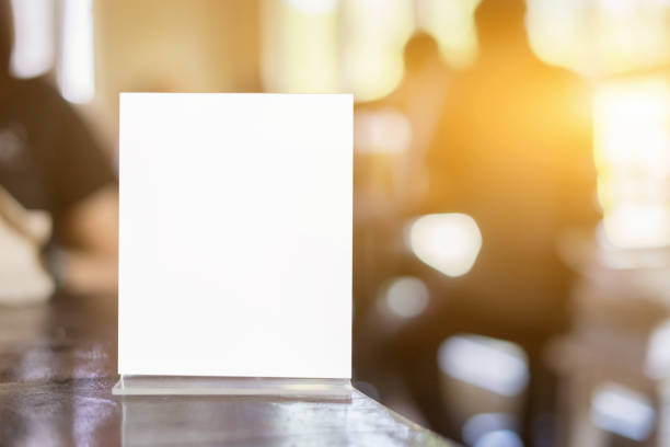 istock Mock up Menu frame on Table in Bar restaurant ,Stand for booklets with white sheets of paper acrylic tent card on cafeteria blurred background 928180638