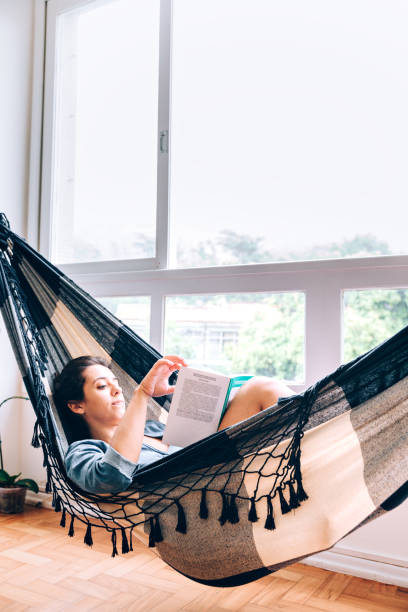 istock Young women reading a book on hammock 928188628